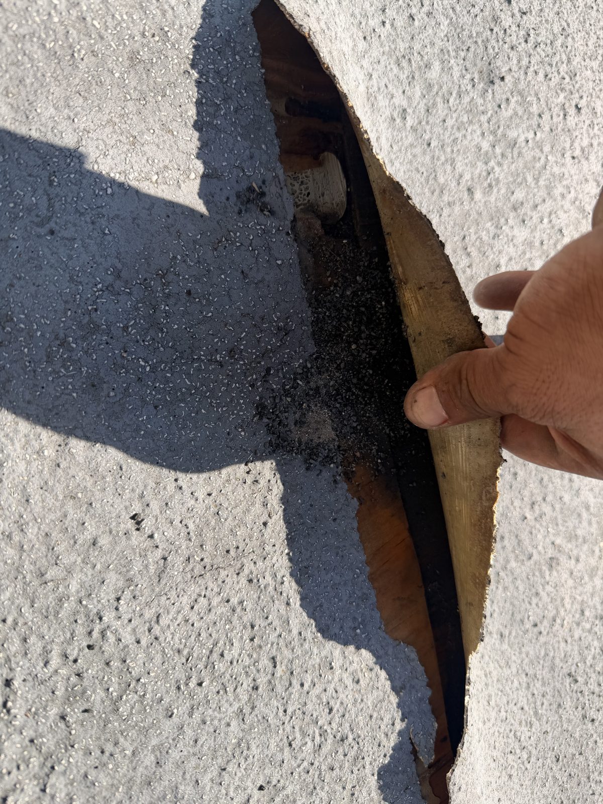 Torn roof membrane pulled back to expose wet and stained wooden decking at the Dana Point repair area.
