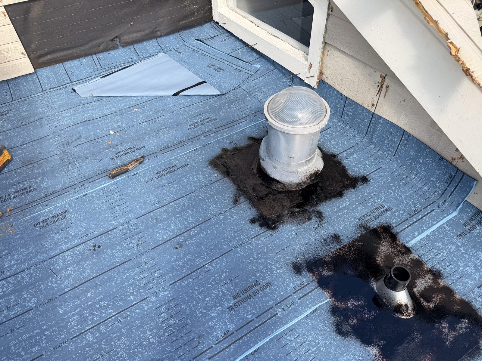 New self-adhered underlayment around the solar tube skylight and vent pipe, with flashing work visible during the repair.